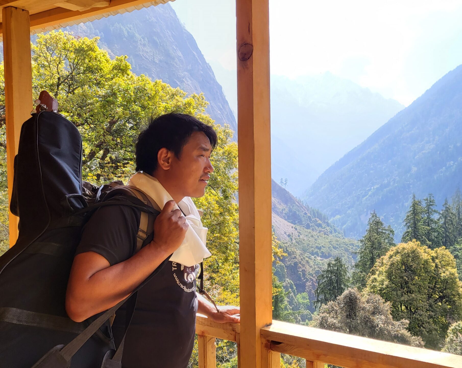 Our Story Lhomi man looking at a beautiful valley on a balcony